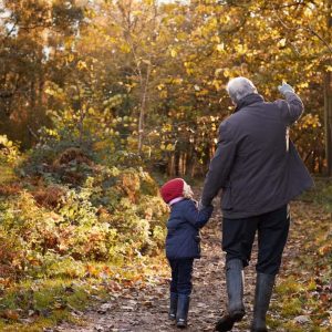Parent/grandparent on a walk in the autumn forest with a child