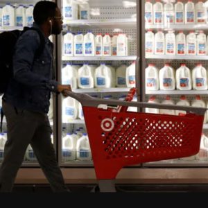 A shopper walks past the milk and dairy display while pushing a Target cart.